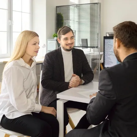 Beratungsgespräch zu dritt an einem Tisch mit Unterlagen