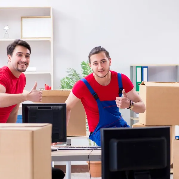 Zwei Umzugshelfer mit Kartons in einem Büro zeigen den Daumen nach oben
