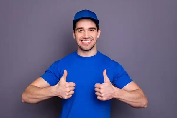 Lächelnder Umzugshelfer im blauen Shirt hebt den Daumen